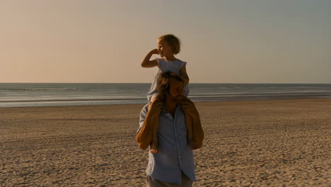 father and daughter enjoying sunset piggyback ride on the beach