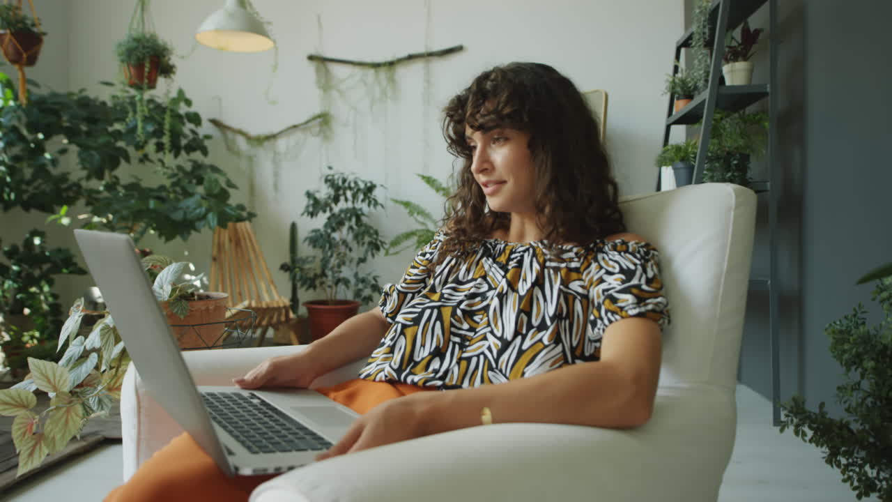 Woman Web Calling on Laptop in Room with Plants