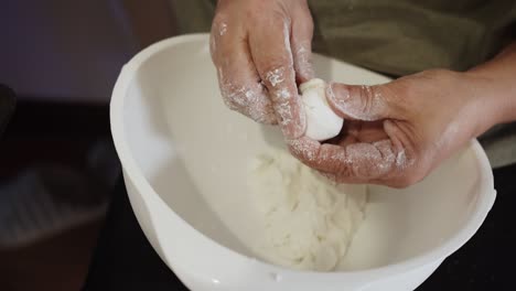 close up hands of pastry chef make flour dough to warp around the coconut filling, thai coconut balls recipe or khanom tom, thai traditional dessert