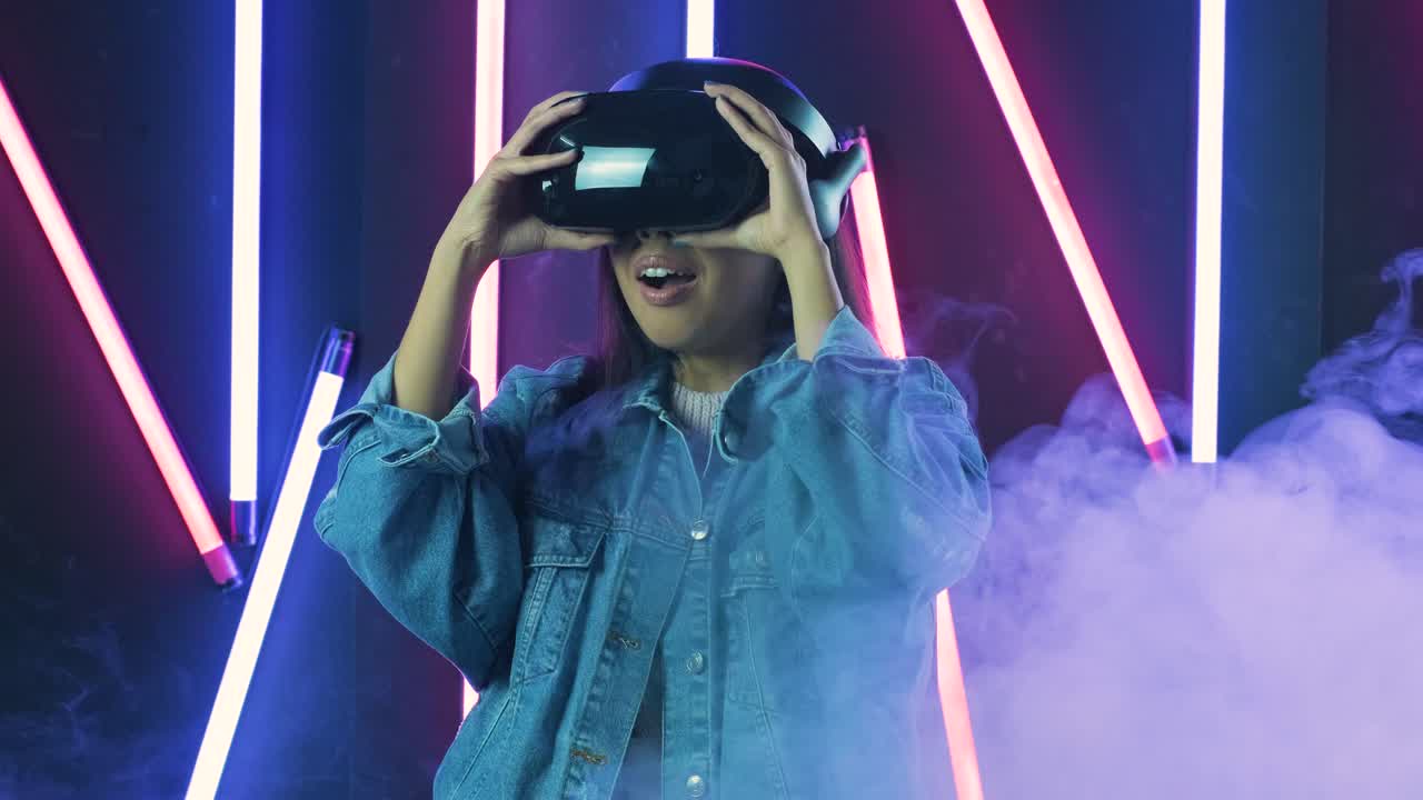una giovane donna si mette le cuffie vr e si chiede come sia fantastico nel mondo vr. casco di realtà virtuale su sfondo di luce a colori fumo