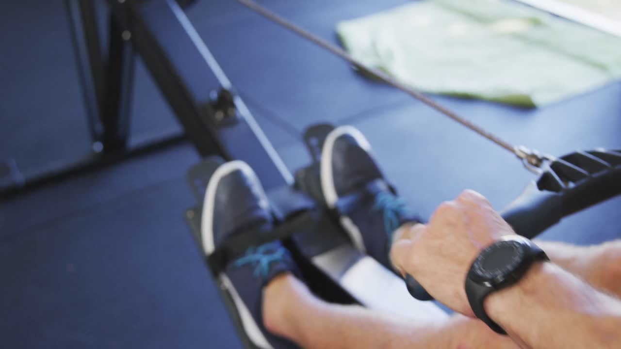 Low section of fit caucasian man exercising, practicing rowing inside gym