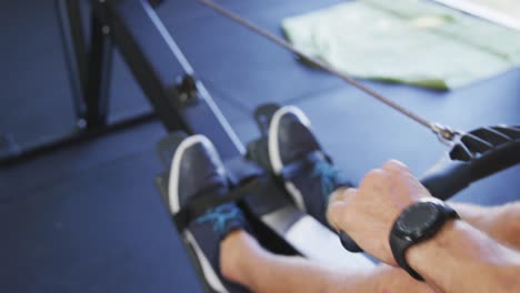 low section of fit caucasian man exercising, practicing rowing inside gym