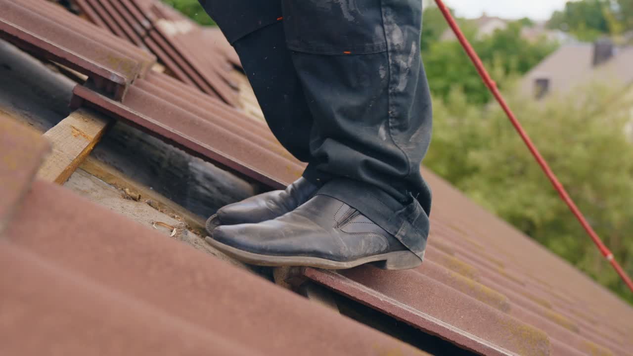 primer plano de la mano del trabajador quitando la teja de la azotea para la instalación del panel solar
