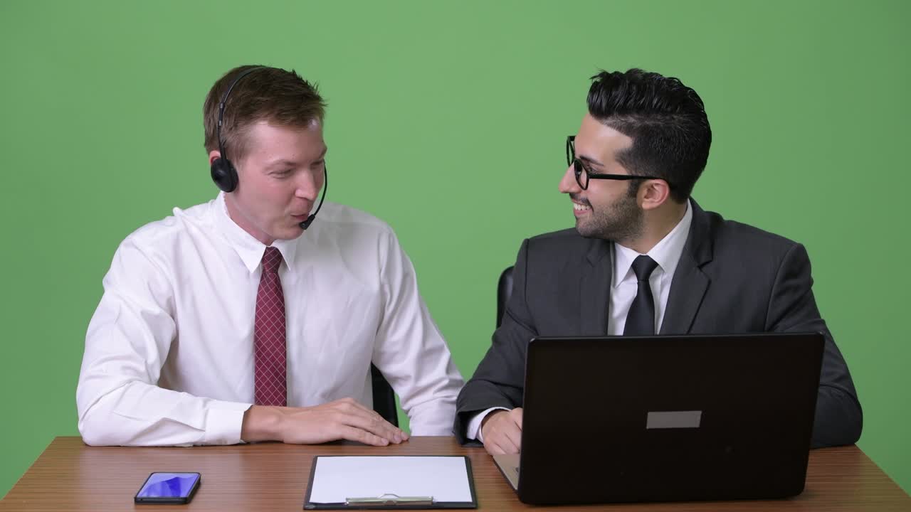 초록색 배경에서 함께 일하는 두 명의 젊은 다민족 사업가