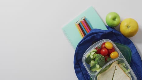 vídeo de un almuerzo sano envasado de frutas y verduras, con lápices de colores en el bolso escolar