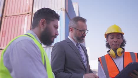 inversor profesional o gerente, discutir con ingeniero masculino y femenino con proceso de carga de carga en tableta. colaborado de la diversidad de socios en el negocio de logística, acordar proyecto, inversión o empleo.