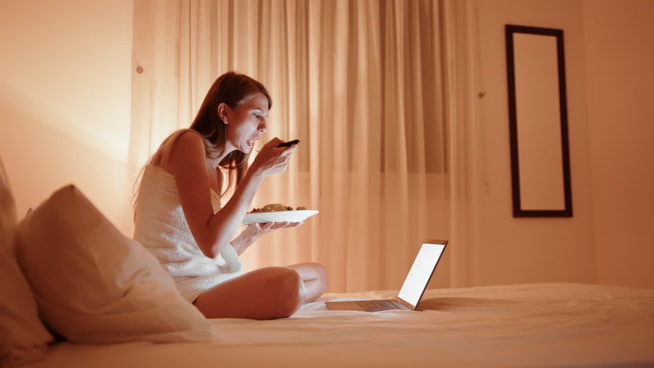 밤에 침대에서 을 먹고 노트북에서 일하는 여자