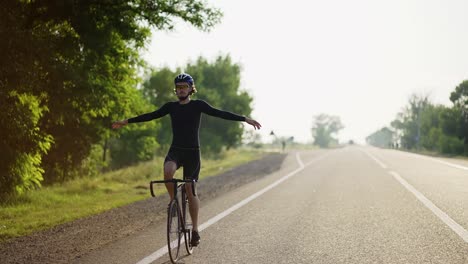 Male-cyclist-in-helmet-rides-bicycle-while-stretching-hands