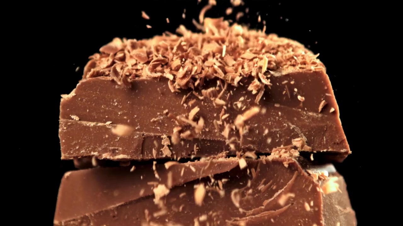 Deliziose scaglie di cioccolato che cadono su una pila di tavolette di cioccolato