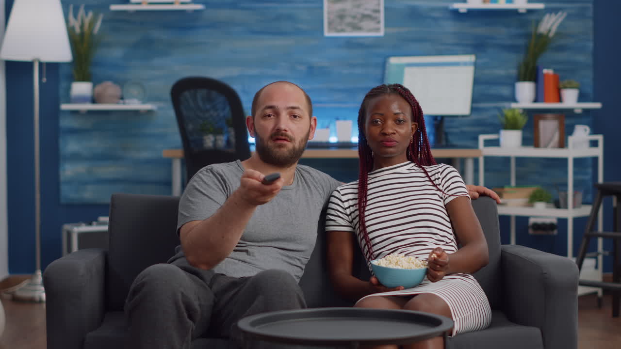 Young interracial couple watching television in living room