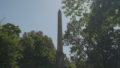 tall landmark obelisk in downtown madrid surrounded by green trees, motion view