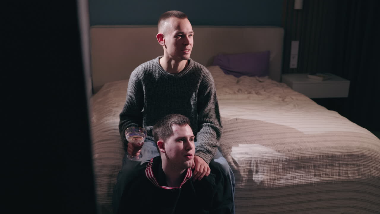 dos hombres viendo la televisión en un dormitorio