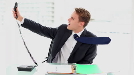 Young-annoyed-businessman-sitting-at-his-desk-working