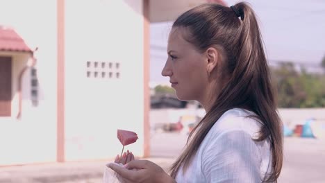 girl in white shirt eats watermelon slice against building