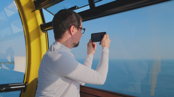 Uomo che scatta una foto della vista sull'oceano da una cabina gialla