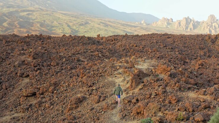 Terreno vulcanico roccioso rosso del pianeta Marte con un sopravvissuto solitario che cammina