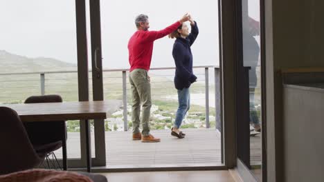 Happy-diverse-couple-holding-hands-and-dancing-together-at-home