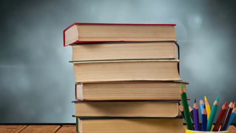 animación de una pila de libros junto a una taza con lápices de colores sobre luces brillantes