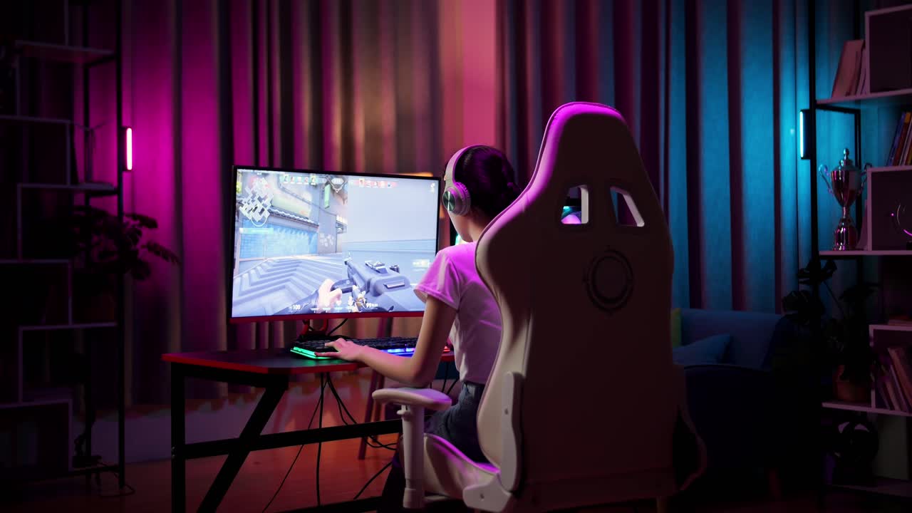 adolescente asiática jugadora que usa auriculares y juega videojuegos en la computadora, videojuegos de disparos en línea