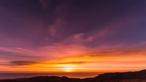 vibrant sunset or sunrise over ocean with starry sky and mountain silhouettes