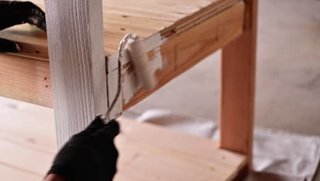 worker with rollerbrush priming wooden table with white primer paint