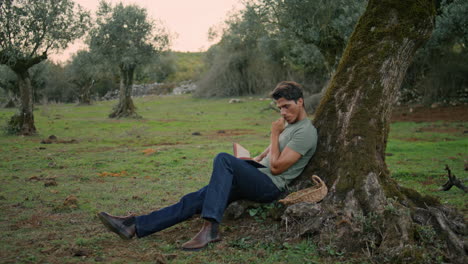 calm farmer reading book sunset nature. relaxed man enjoying novel vertically