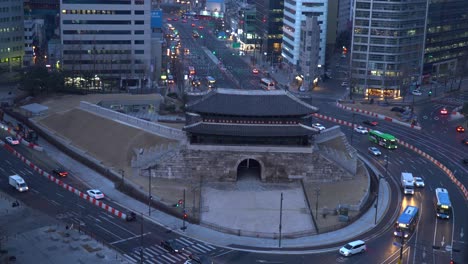 autobuses y automóviles que pasan rápidamente por la intersección de carreteras frente a la puerta de sungnyemun en la ciudad de seúl, corea del sur