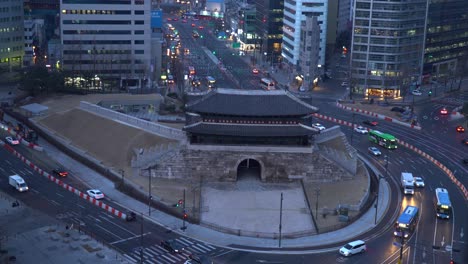 buses and cars fast passing road intersection in front of sungnyemun gate in seoul city, south korea