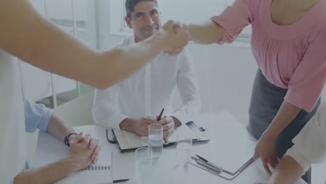 Pie-graph-against-mid-section-of-two-businesswomen-shaking-hands-at-office