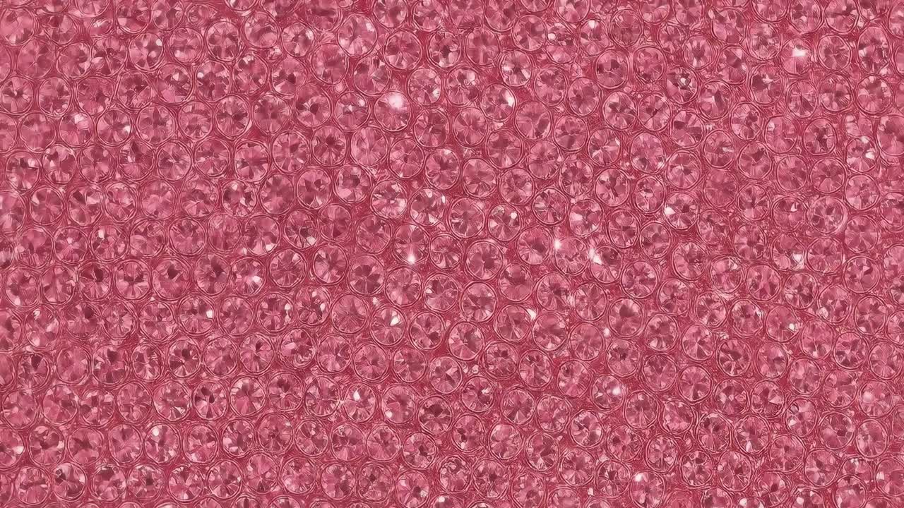 Top-down video shot of sparkling pink crystals, creating a vibrant, textured surface