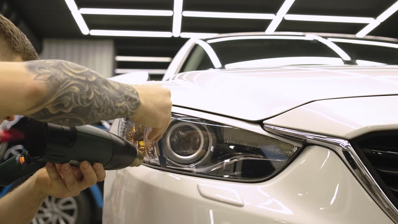 hombre cubriendo el coche con cinta de poliuretano de vinilo. películas para el coche. pegatina película protectora en el faro del coche