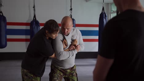 hombre caucásico aprendiendo artes marciales de un entrenador en el gimnasio