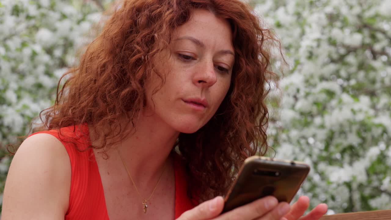 Kvinde bruger telefon i en forårspark