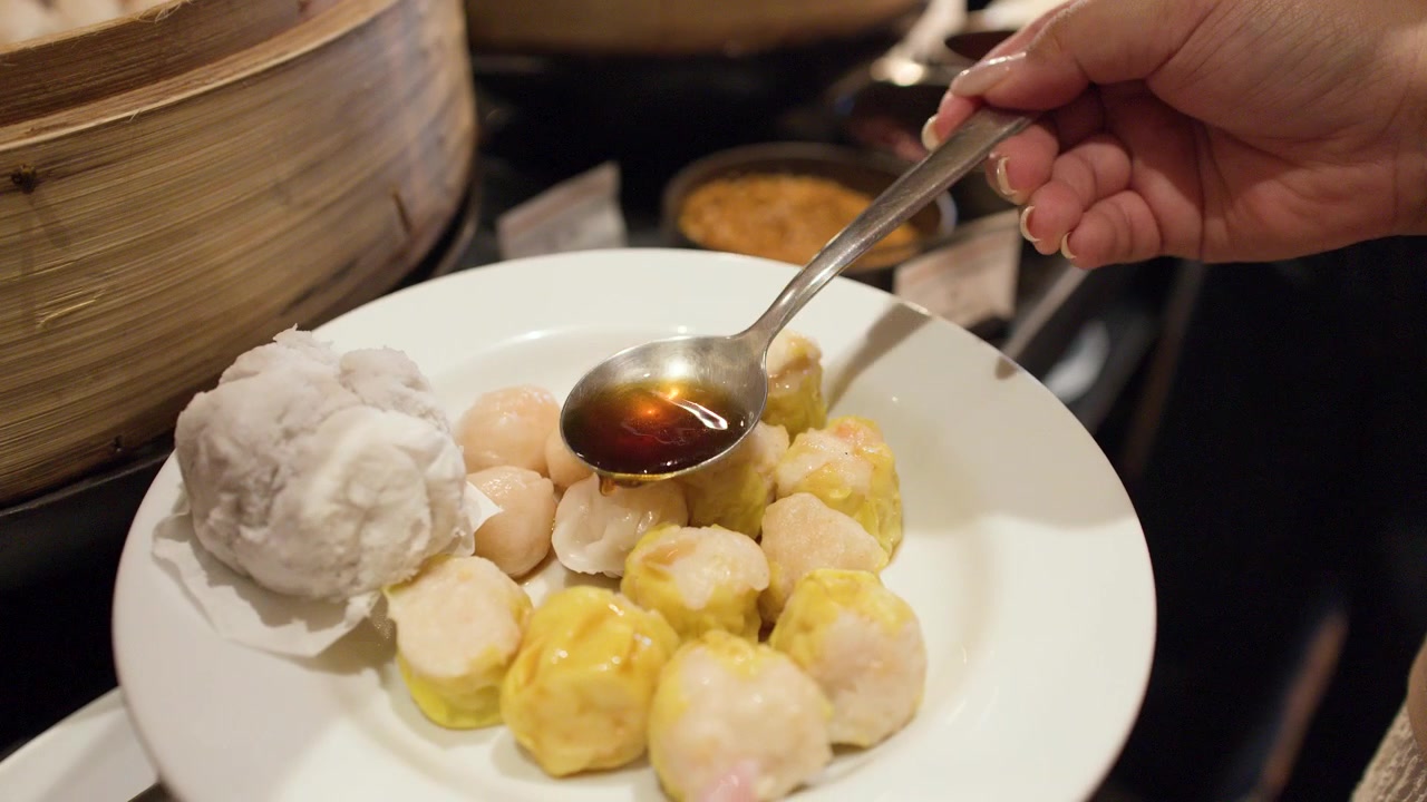 Pessoa Regando Molho de Soja Sobre Bolinhos Dim Sum Cozidos no Vapor