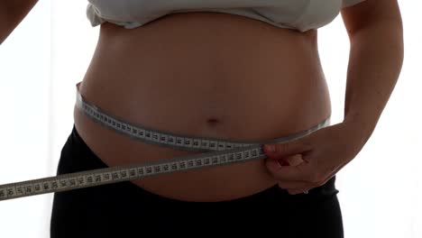 pregnant woman measuring her belly with a tape. medium shot