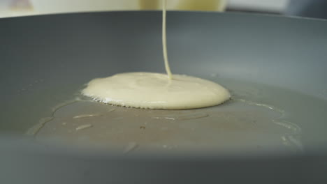 close-up pouring sticky pancake batter into a hot frying pan