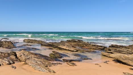 ondas a bater na praia rochosa sob um céu claro