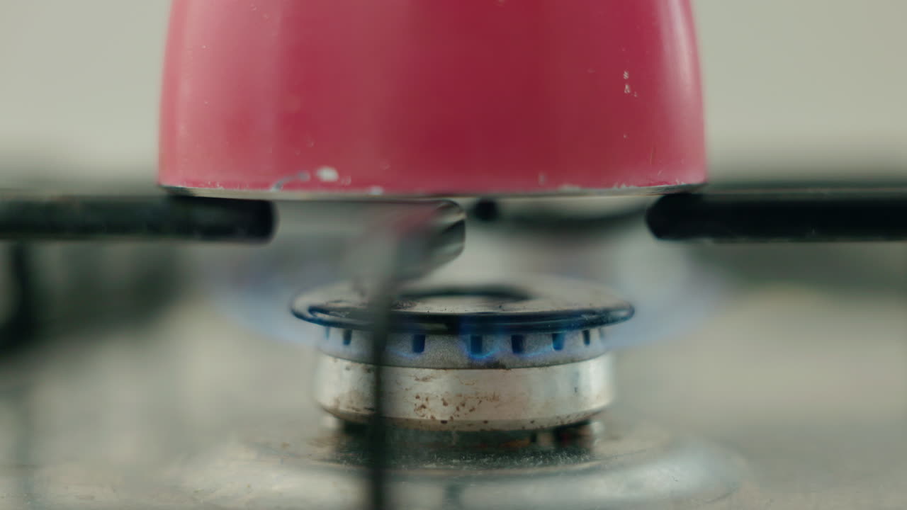 Close-up of a gas stove with a red pot on it