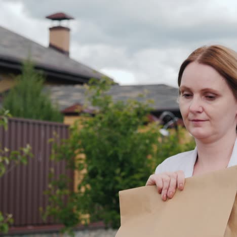 a young woman carries bags of groceries to her home