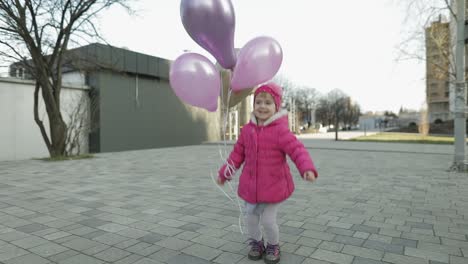 happy child jumping at the street with balloons with helium