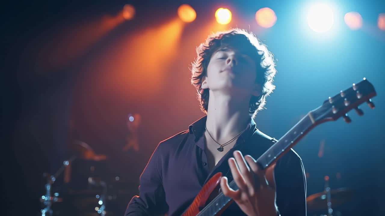 Giovane musicista suona la chitarra elettrica sotto luci di scena colorate. I suoi occhi si chiudono mentre si concentra sulla sua performance. Un morbido riflettore illumina il suo viso e il suo strumento.