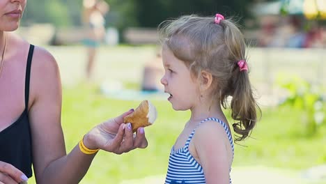 close-up slow motion woman gives little girl to eat ice cream the girl in swimsuit