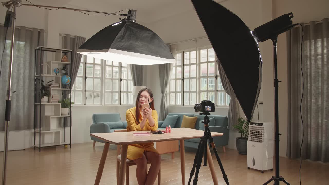 Beauty Blogger Woman Filming Daily Make-Up Routine Tutorial On Camera. Influencer Girl Live Streaming Cosmetics Product Review In Home Studio With Professional Lighting Equipment. Vlogger Job