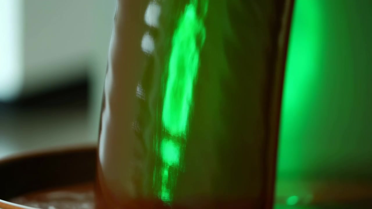 Primo piano estremo di una superficie cilindrica rossa lucida che mostra riflessi colorati cangianti che scorrono su una curva liscia, con finitura riflettente, contrasto morbido e un aspetto commerciale astratto ed elegante.