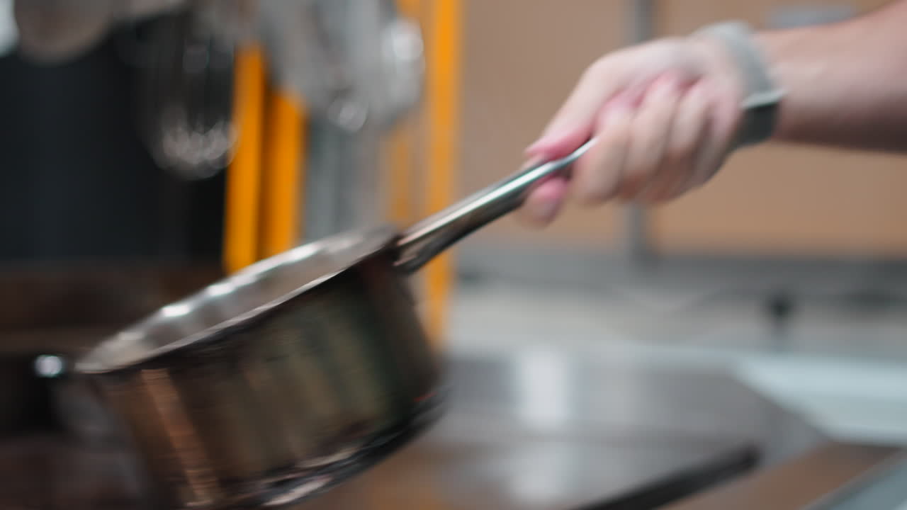 Image of a hand holding a stainless steel pot