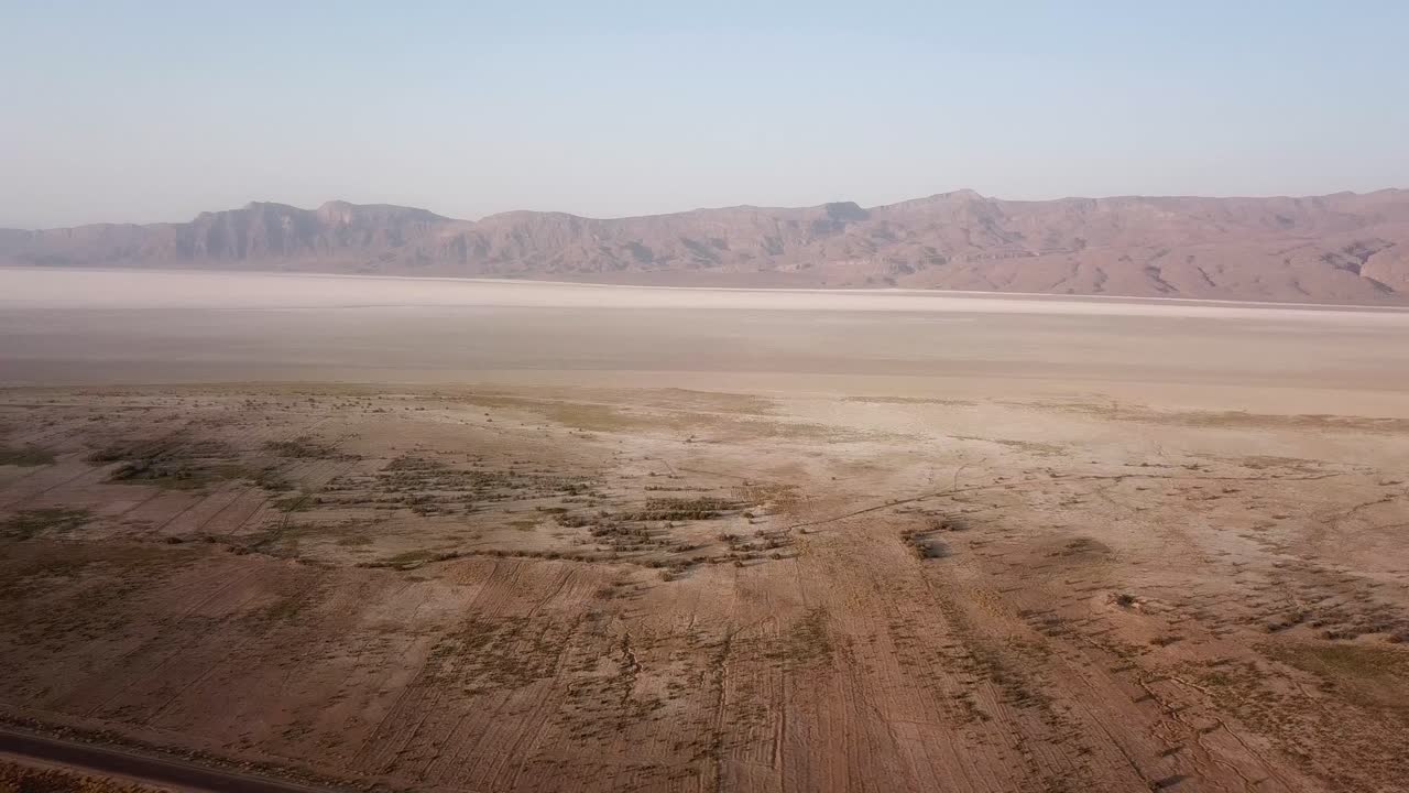 Drone shot wonderful salt lake in Middle east asia desert landscape wide panoramic view of skyline in hazy day Fars countryside in rural village mountain in summer season in Iran white salt mineral