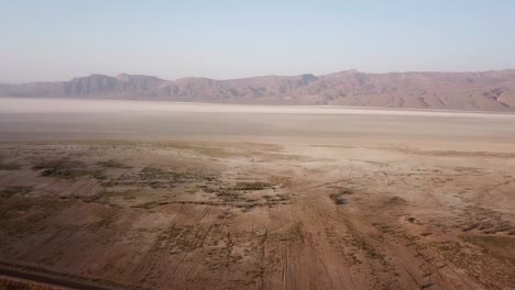 Un-Dron-Disparó-Un-Maravilloso-Lago-Salado-En-El-Medio-Oriente,-Asia,-Paisaje-Desértico,-Amplia-Vista-Panorámica-Del-Horizonte-En-Un-Día-Brumoso,-Campo-Lejano-En-Una-Aldea-Rural-De-Montaña-En-La-Temporada-De-Verano-En-Irán,-Mineral-De-Sal-Blanca.