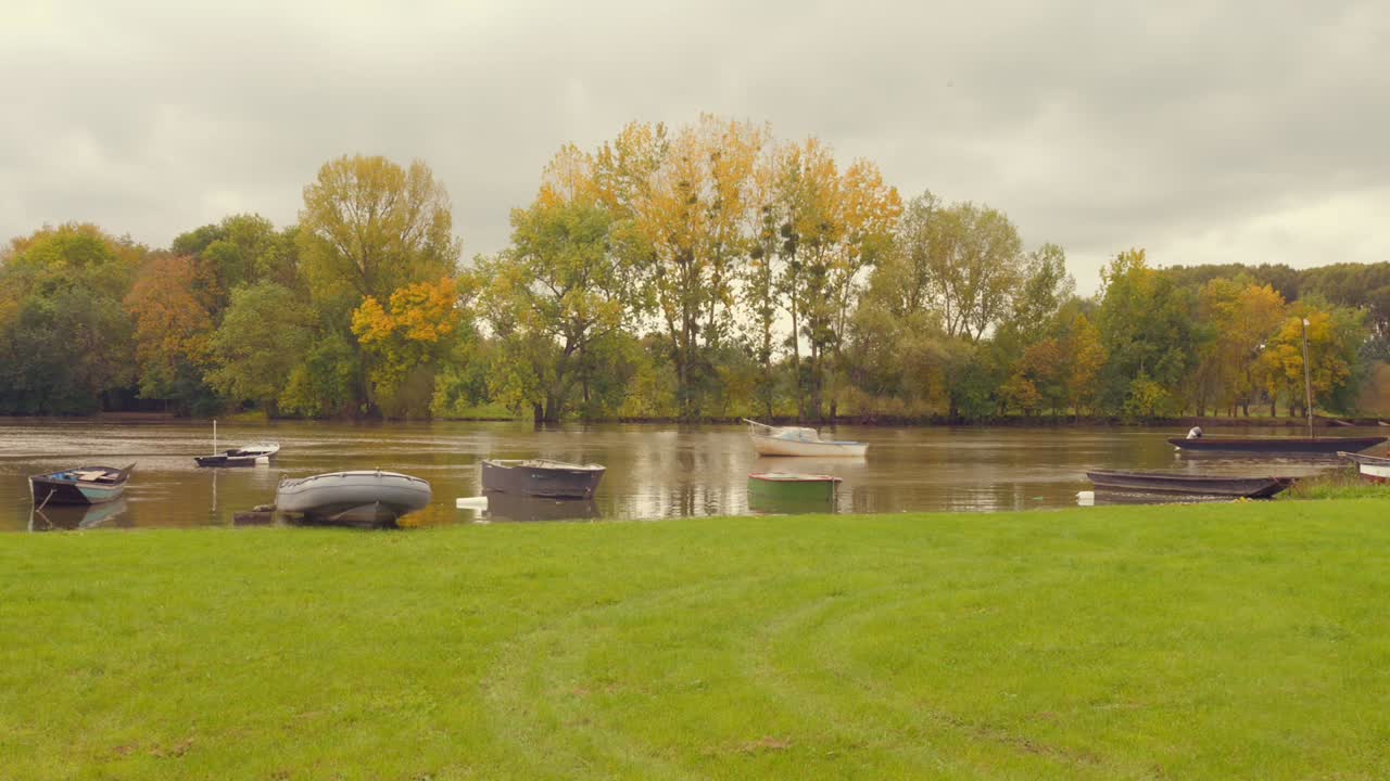 Capturing of boats halted by the banks of Maine river in Angers, France with lush greenery at bacxkground.