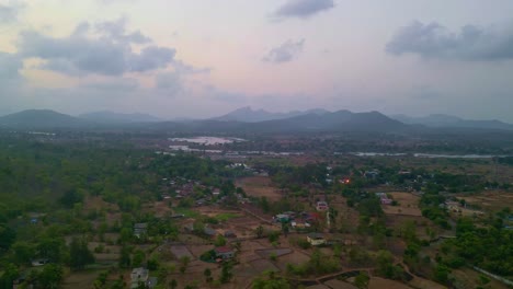 A-beautiful-aerial-view-of-rural-terrace-farming-on-hilly-landscapes-near-Tansa-river-and-cloudy-blue-sky-Shiravli-Maharashtra,-India-4K