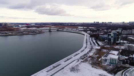 snowy embankment of large city on bank of tranquil river